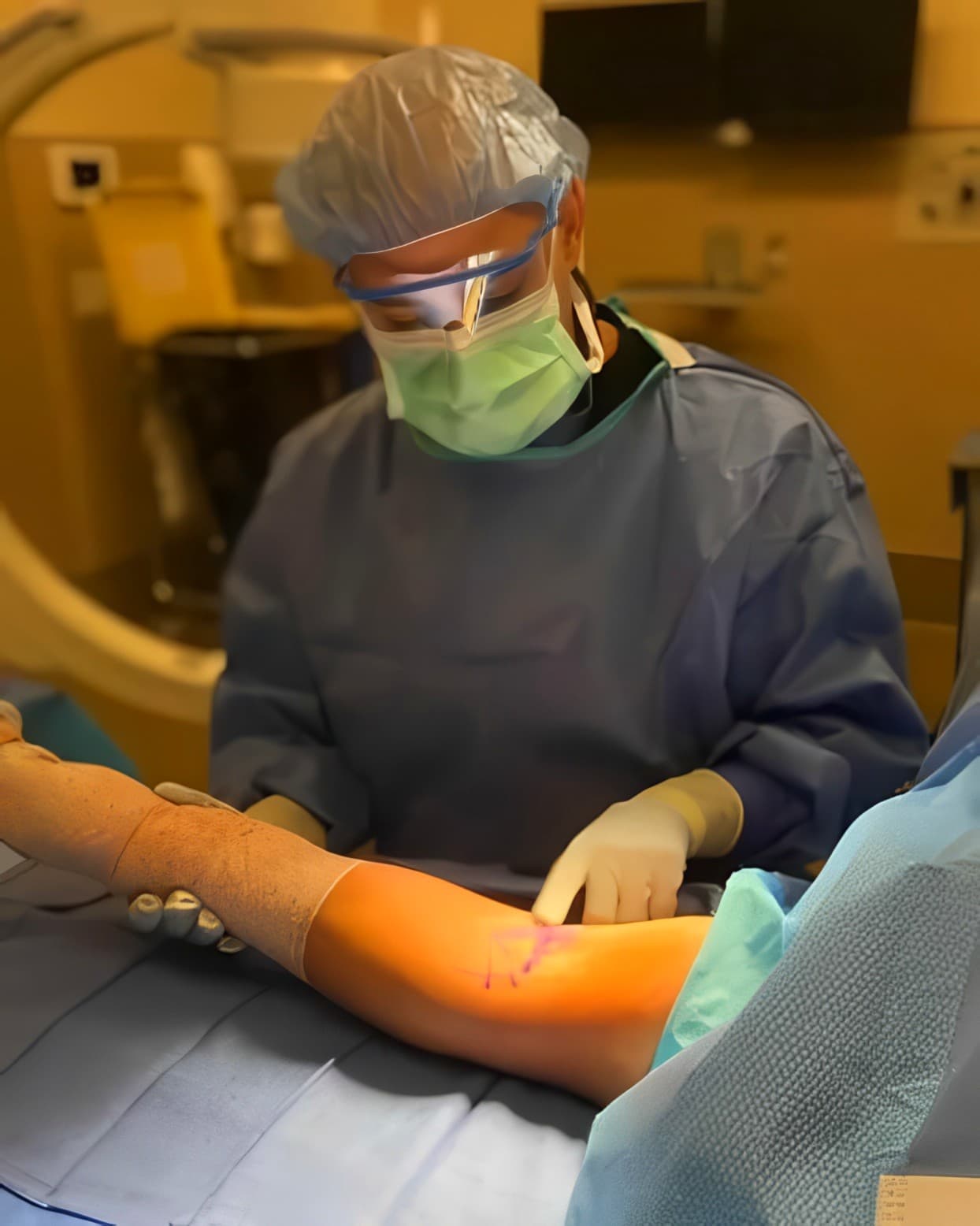 Dr. Abbasi in the operating room, gowned and gloved at the table